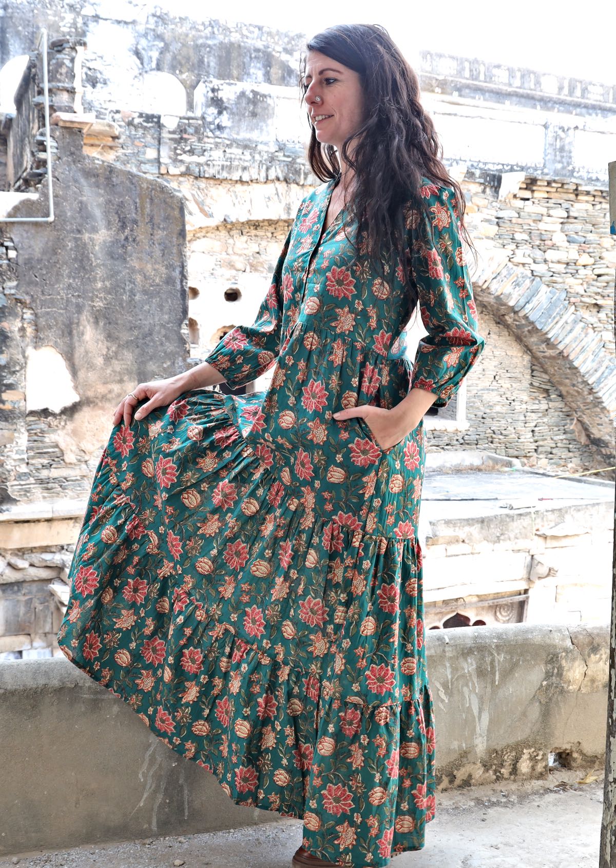 Model flaunting a jade green based floral printed cotton dress with 3 tiers, V neckline and pockets