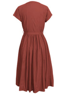 Back view of rust cotton dress with short sleeves, waist tie and small pleats at center of the waist