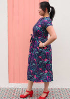 Woman standing in Navy cotton floral maxi dress with belt and hands in pockets