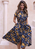 Model flaunting a 100% cotton floral button through dress with short sleeves, pockets and a removable fabric waist tie.