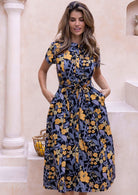 Model wears black button through cotton dress with mandarin collar short sleeves and hands in pocket.