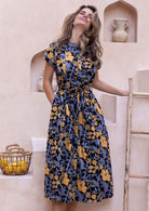 Woman wearing a floral 1950's inspired  cotton dress with mandarin collar that can folded to form V neckline, short sleeves and pockets.