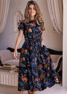 Woman wearing a retro style dark floral dress with short sleeves, pockets and high round neckline.