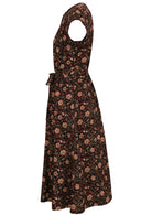 Side image of black floral printed cotton dress with short sleeves, waist tie and pockets.