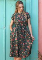 Woman flaunting a 100% cotton dress with floral print and hand in pocket..