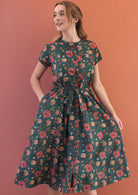Model wears floral printed cotton dress in dark green colour.
