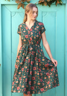 Model wears green cotton dress with folded V-neck, short sleeves and pockets.