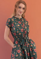 close look of button through vivien dress in dark green based floral print with pockets and belt.