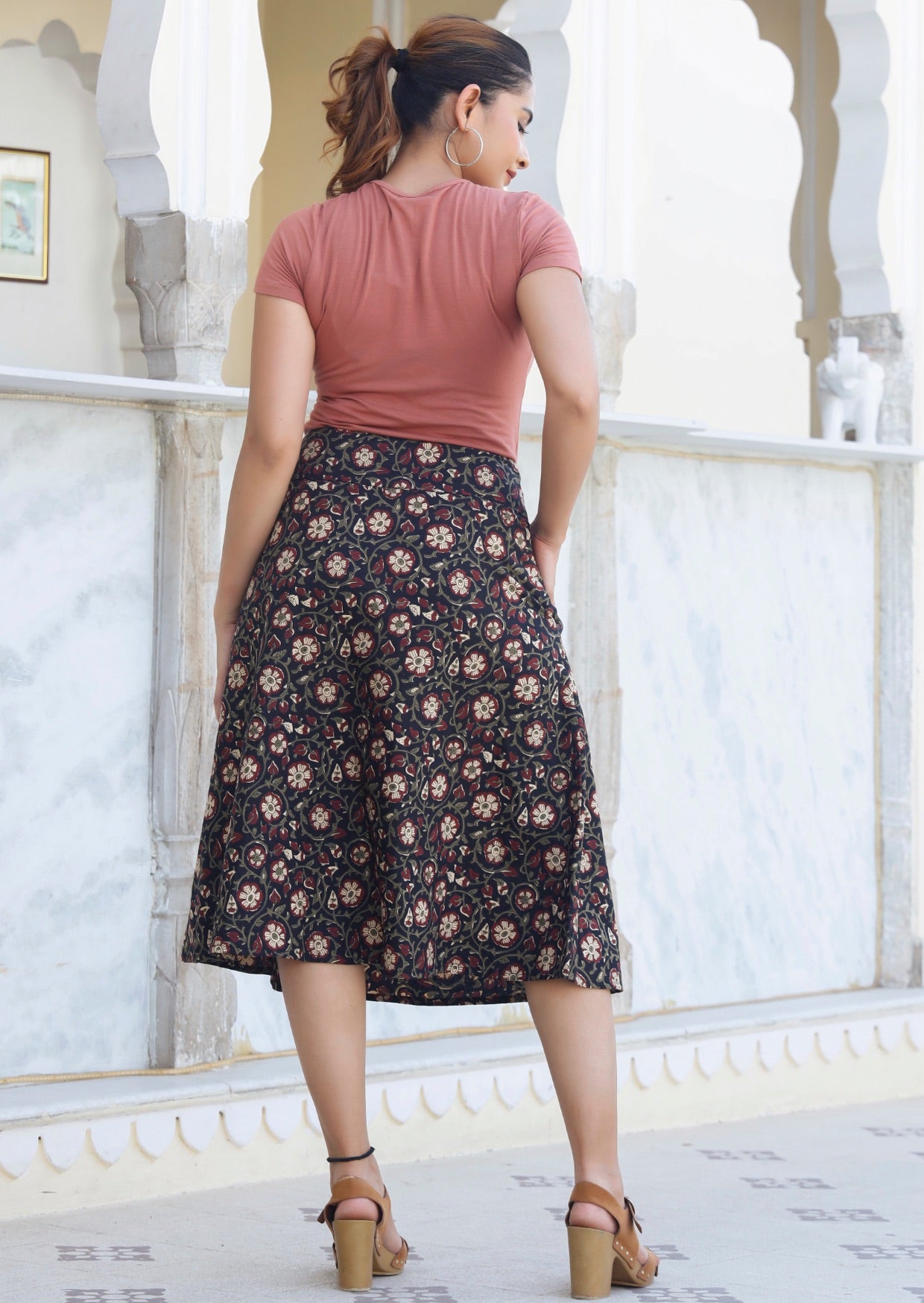 Back image of model in A line cotton skirt in black based floral print, paired with dusty rose basic top.
