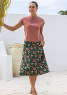 Model wearing 100% cotton A line skirt in deep green with gorgeous pinkish floral print and hand in pocket.