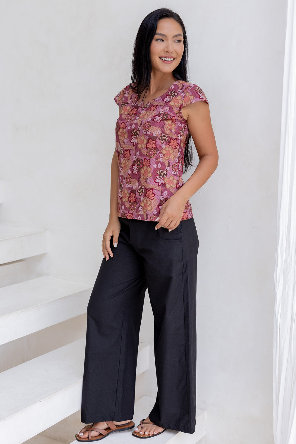 Model posing in a floral print tailored cotton top with cap sleeves, round neckline and length sitting at the hip