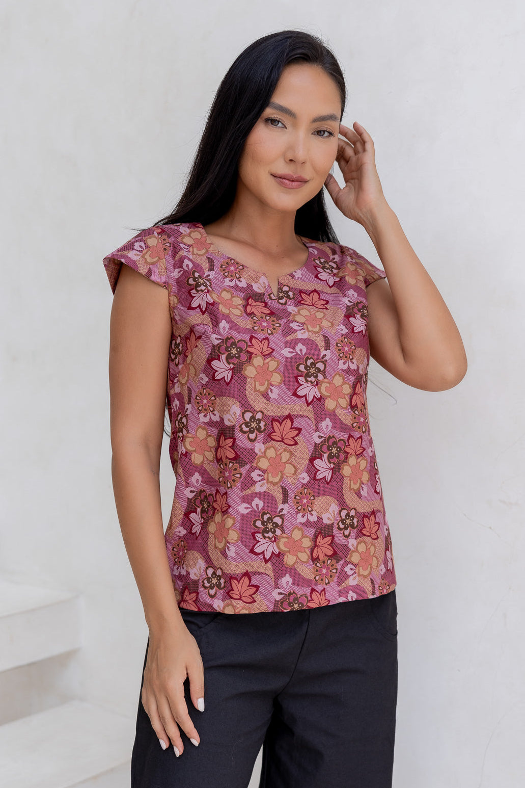 A woman poses in a cap-sleeved cotton tailored top with a Japanese style floral print