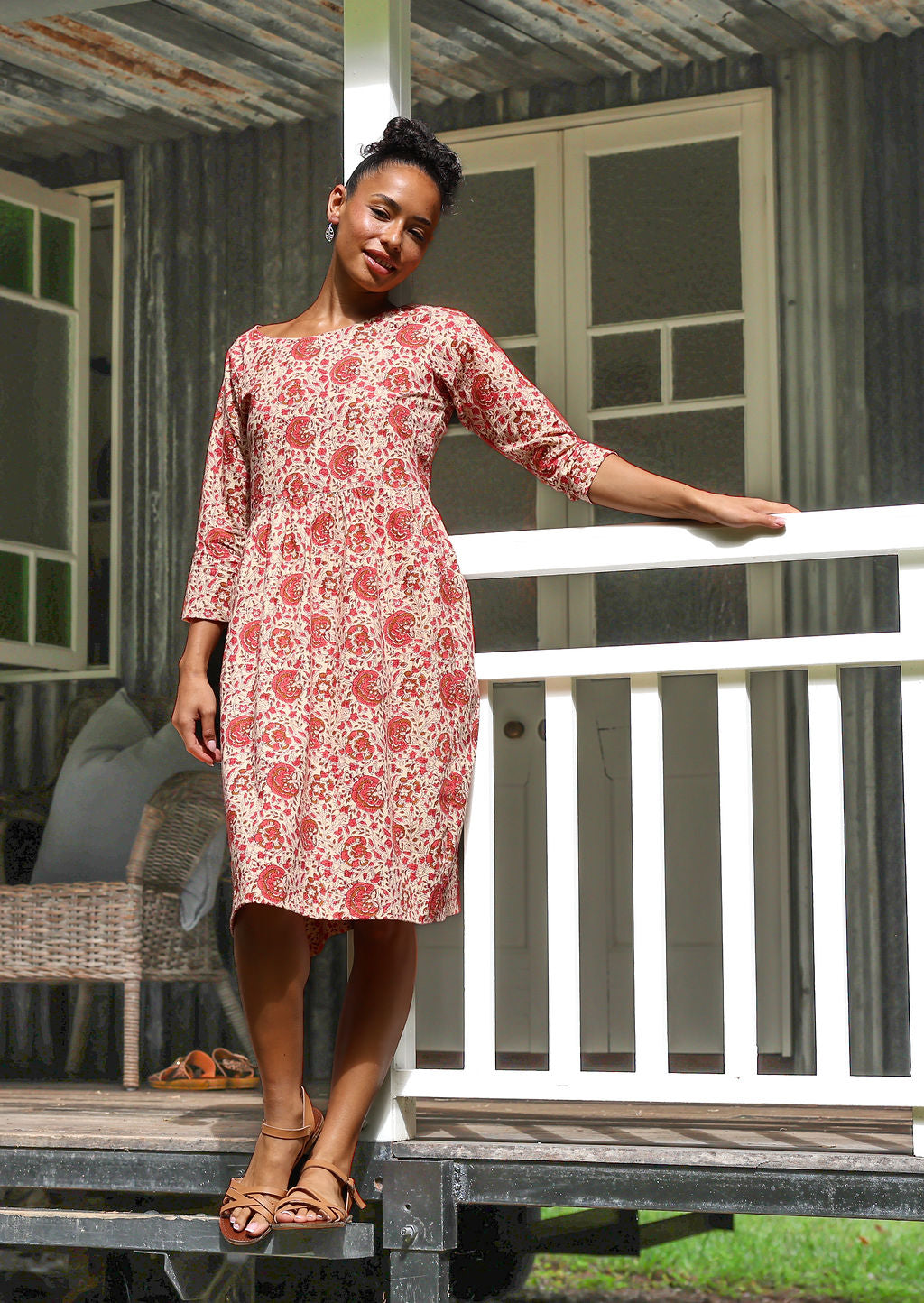 Woman in cotton, floral, knee length sundress with sleeves and pockets