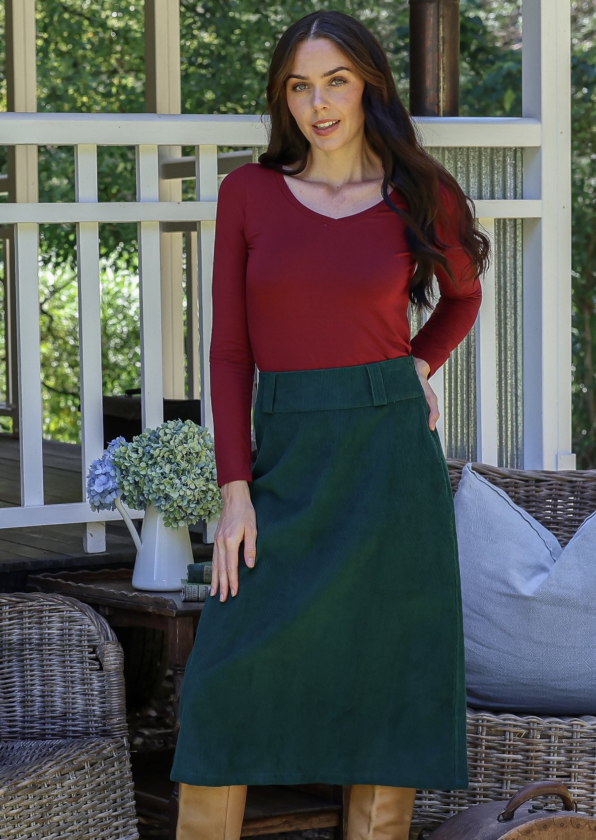 Woman in a red top and green cotton corduroy A-line midi length skirt with belt loops
