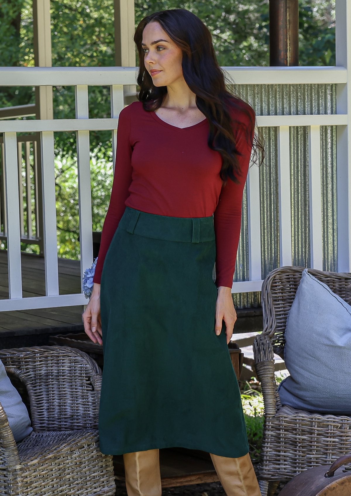 Woman in a red top and green cotton corduroy A-line midi length skirt with belt loops