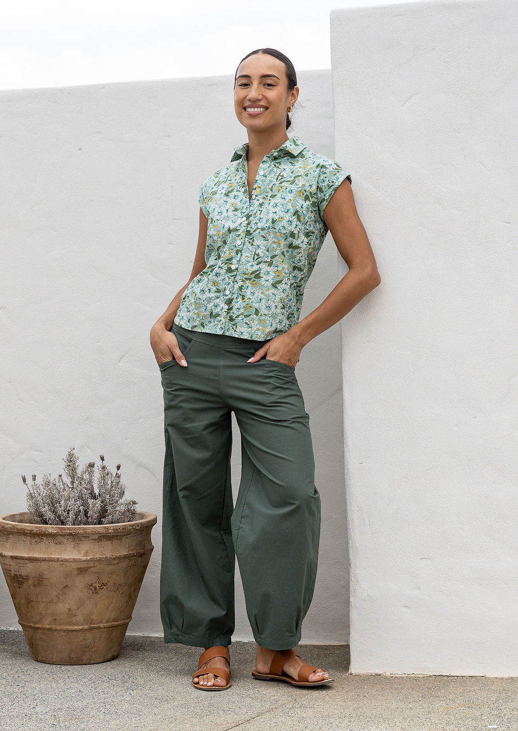 Woman wearing a slim fit button up shirt with shell buttons, structured collar and folded cuff sleeves