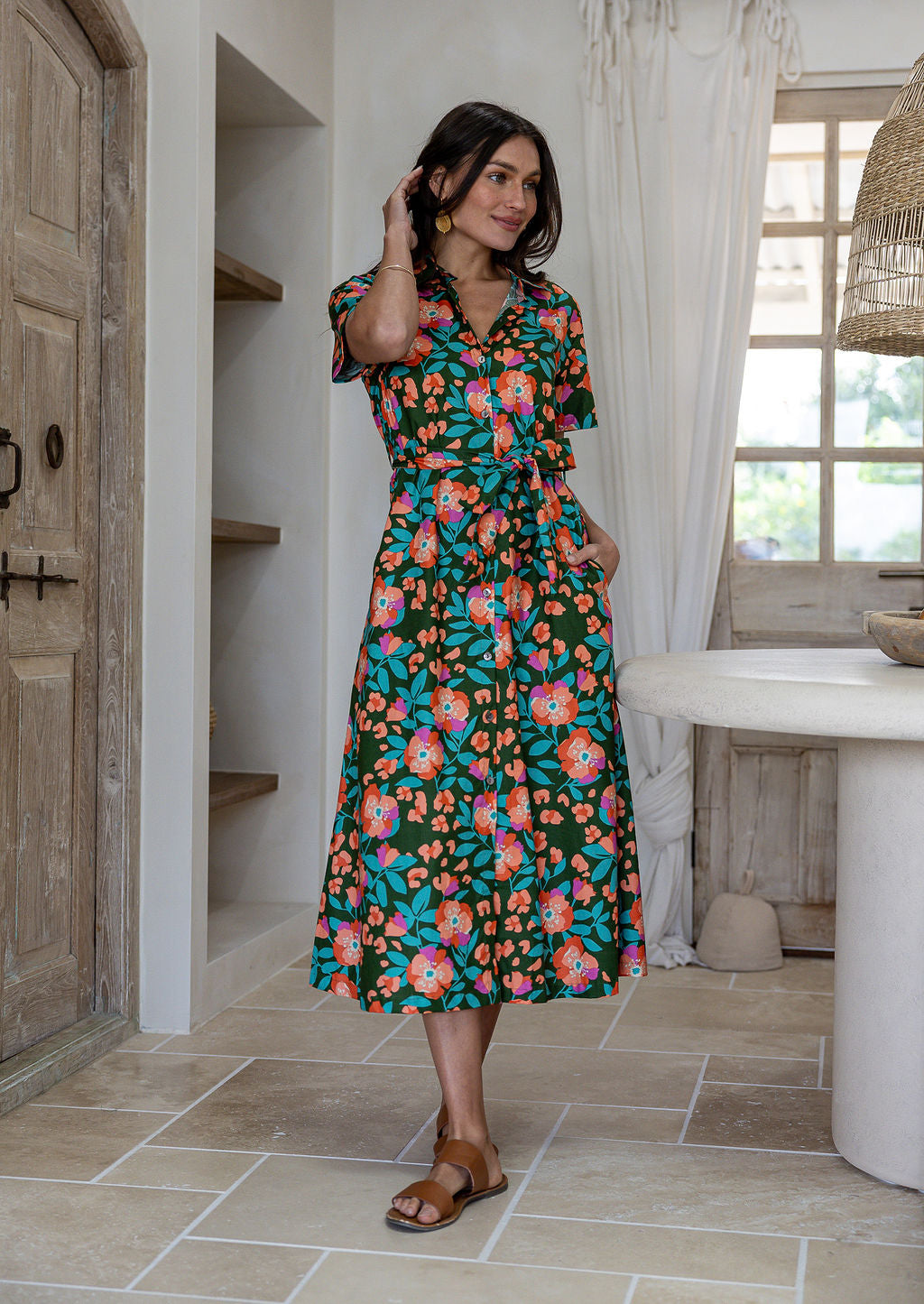 Model standing with one hand in pocket wearing a floral printed shirt dress with detachable fabric belt and short sleeves