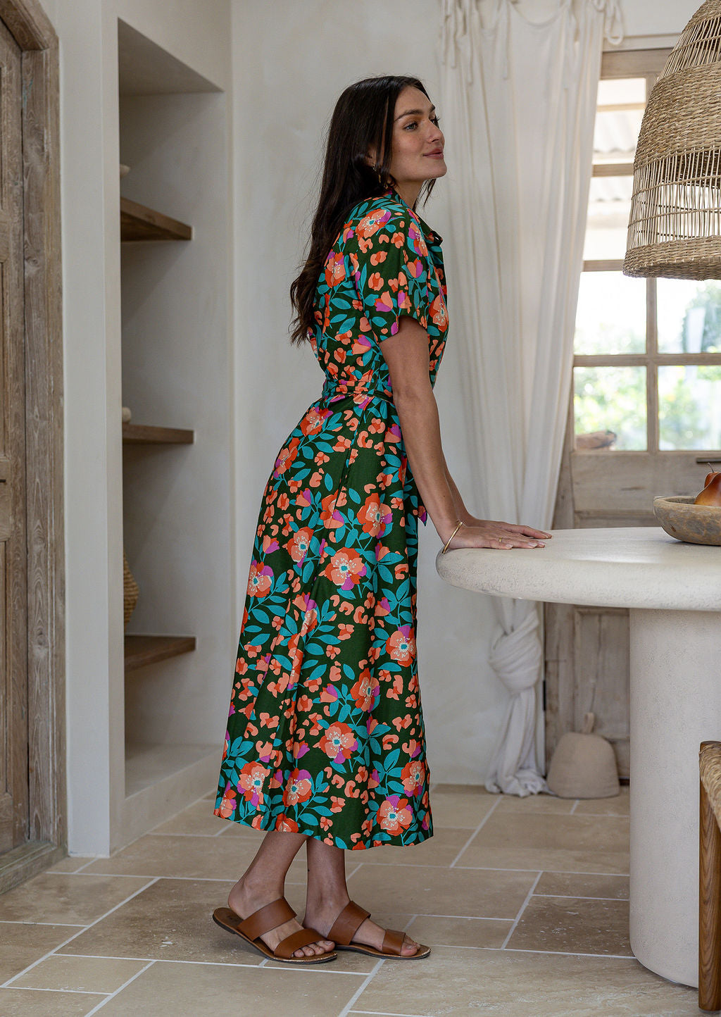 Model standing sideways wearing a floral printed shirt dress with detachable fabric belt and short sleeves