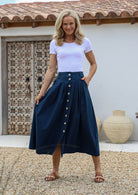 Woman wears 100% cotton, button through long skirt in sea blue with belt loops, box pleats and pockets.