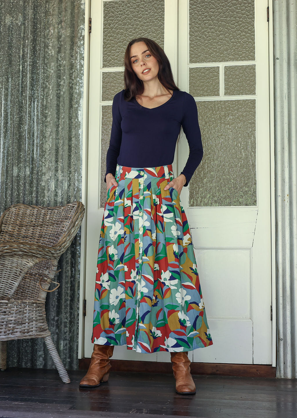 Woman wearing a navy blue basic top and floral button through shin length cotton skirt with box pleats, belt loops and pockets.