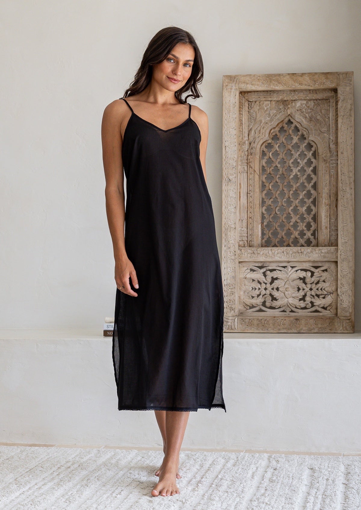 Woman wears black cotton voile maxi slip with V-neckline, spaghetti straps and side splits