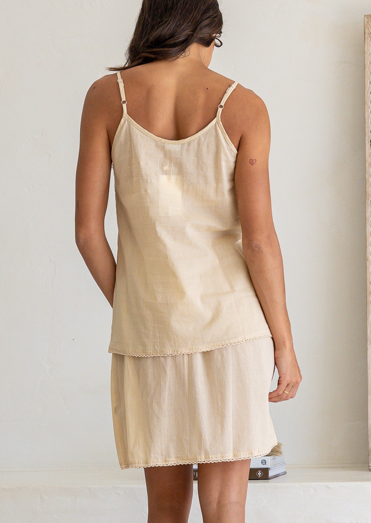 Back view of woman in a nude toned cotton voile above knee slip skirt with picot trim, paired with a matching cami