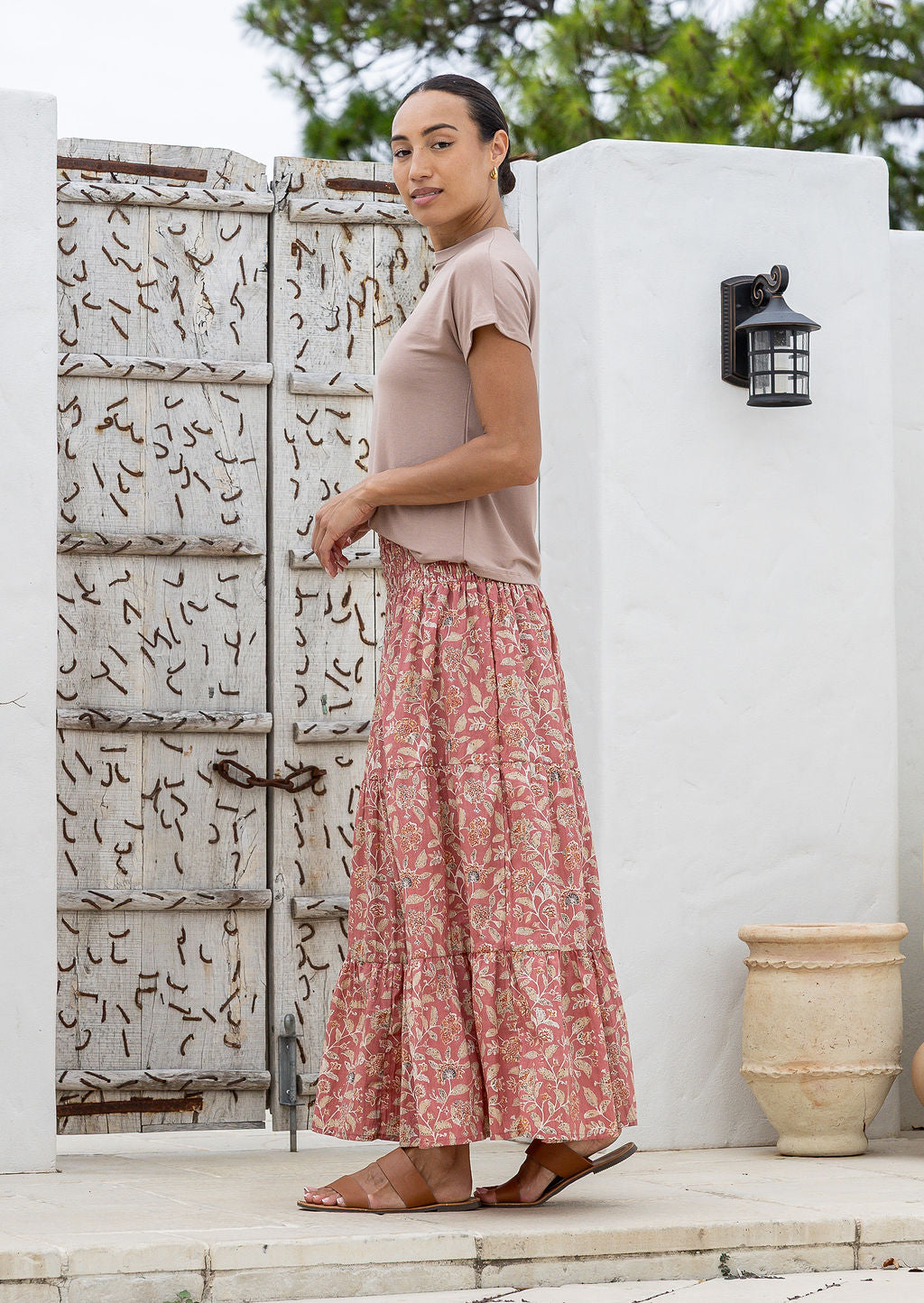 Model standing sideways wearing a three tiered, cotton maxi skirt with plain basic top