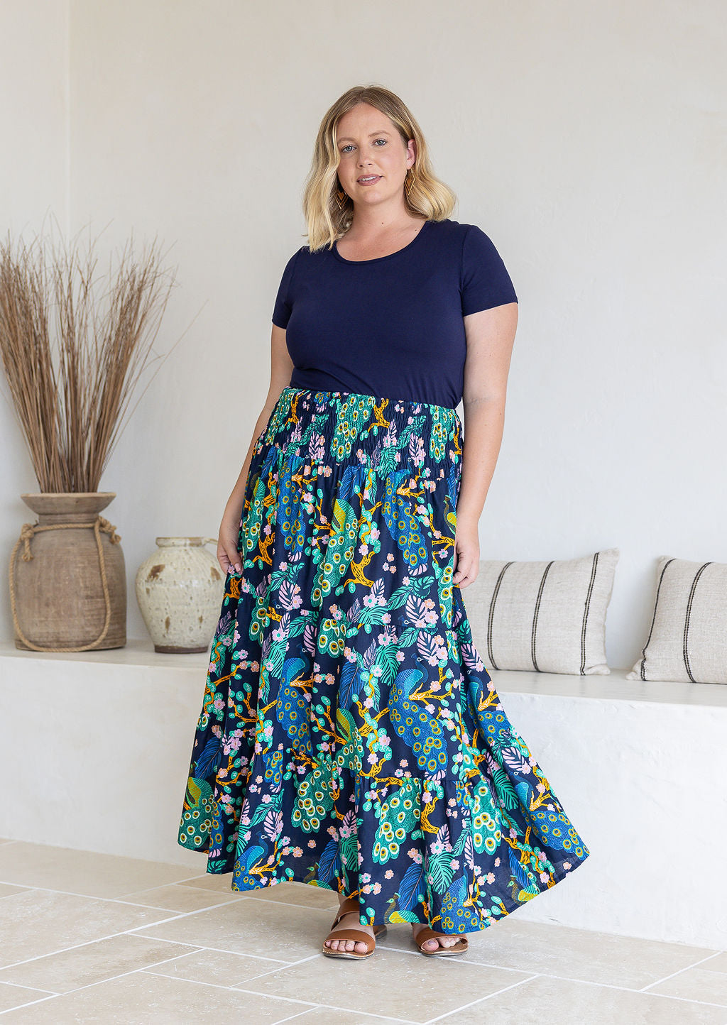 Model standing sideways wearing a three tiered, cotton maxi skirt with plain basic top