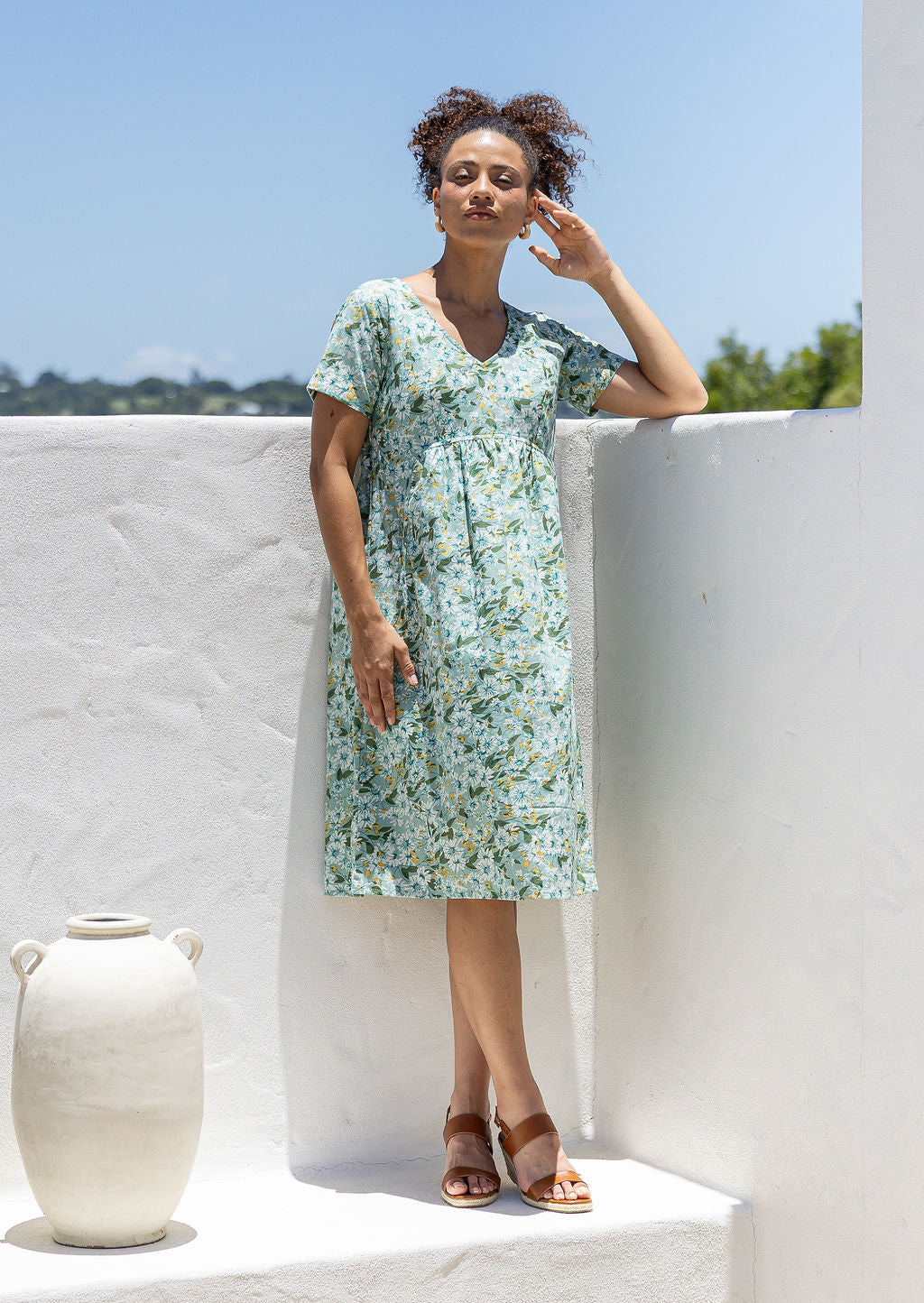 Model wearing a cotton knee length dress with empire waist, short sleeves and pockets.