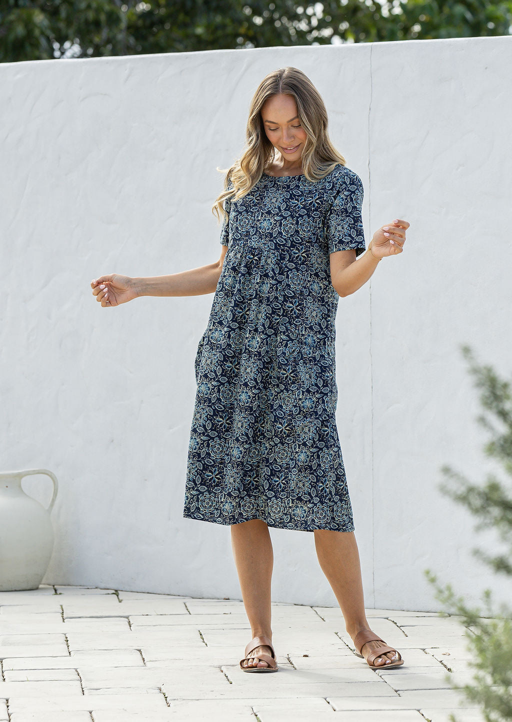 Woman poses in a blue based cotton floral short sleeve dress with round neckline