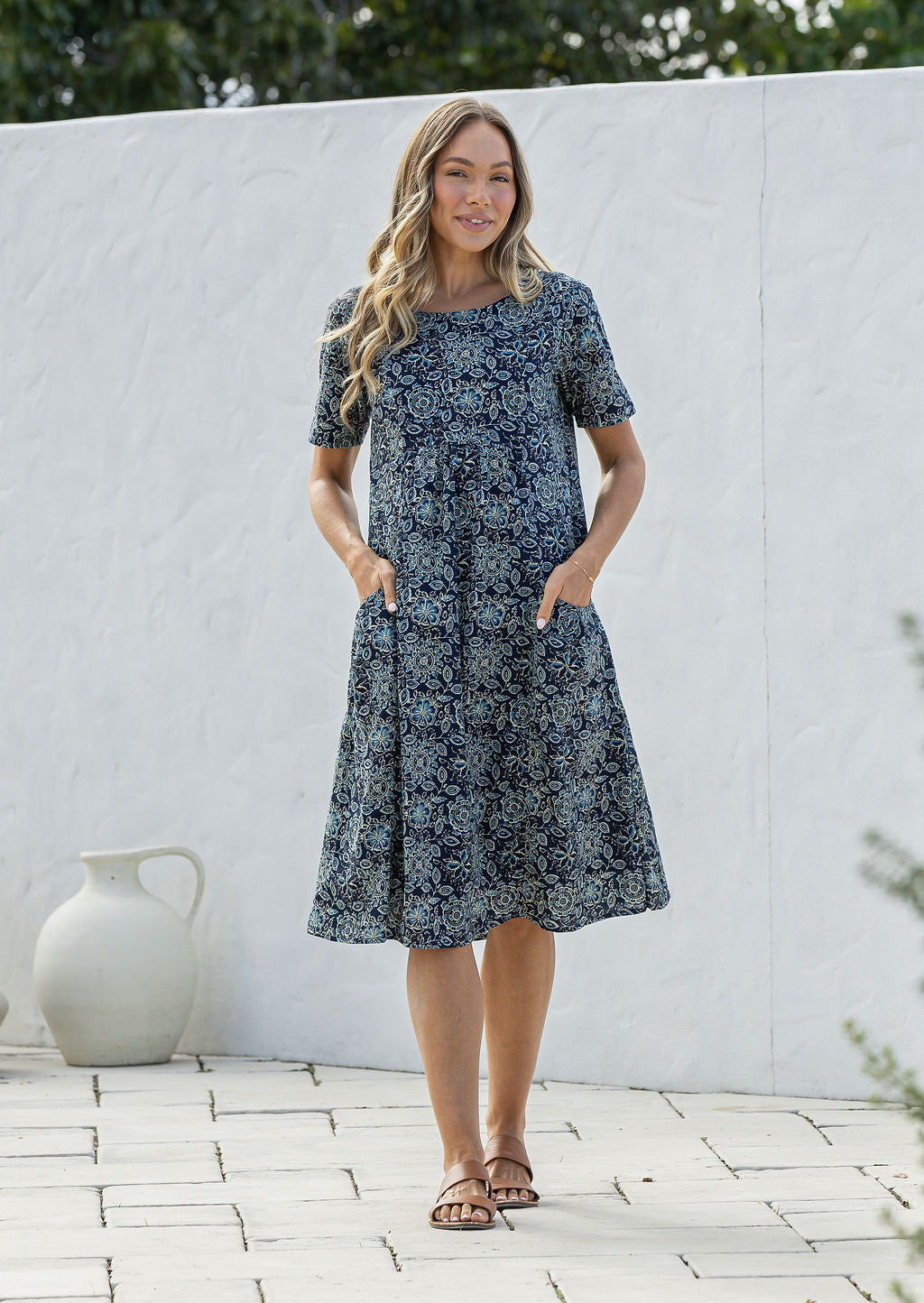Woman wearing a navy blue based floral print cotton dress with hands in pocket