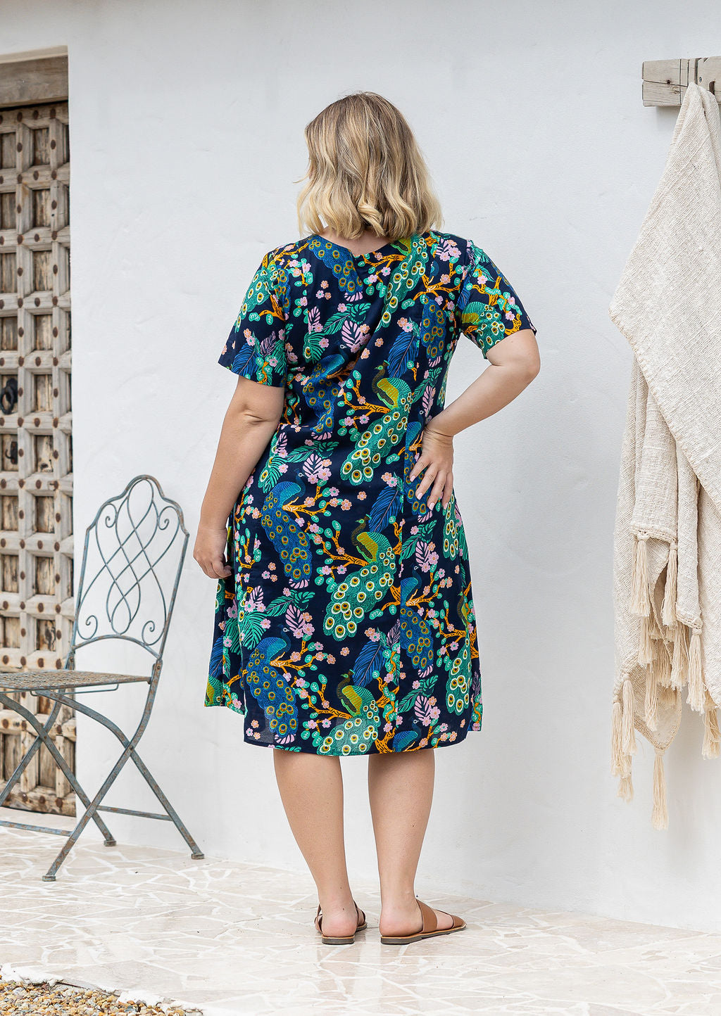 Woman stands backwards wearing a 100% cotton lightweight lined relaxed fit knee length dress.