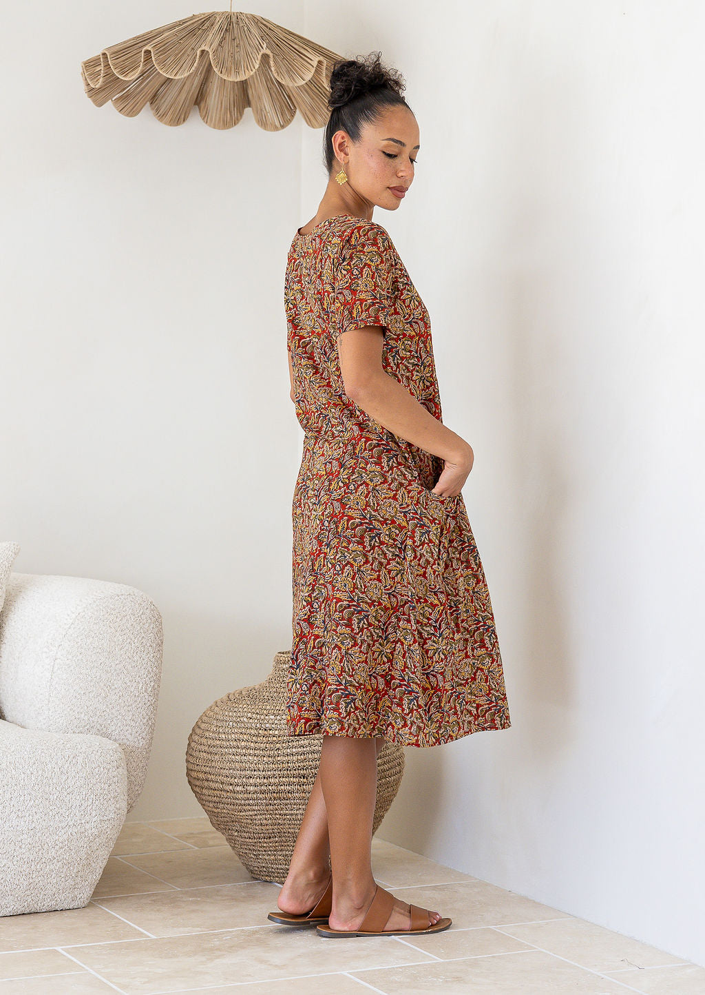 Woman wearing a patterned floral cotton dress with her hands in the pockets side view