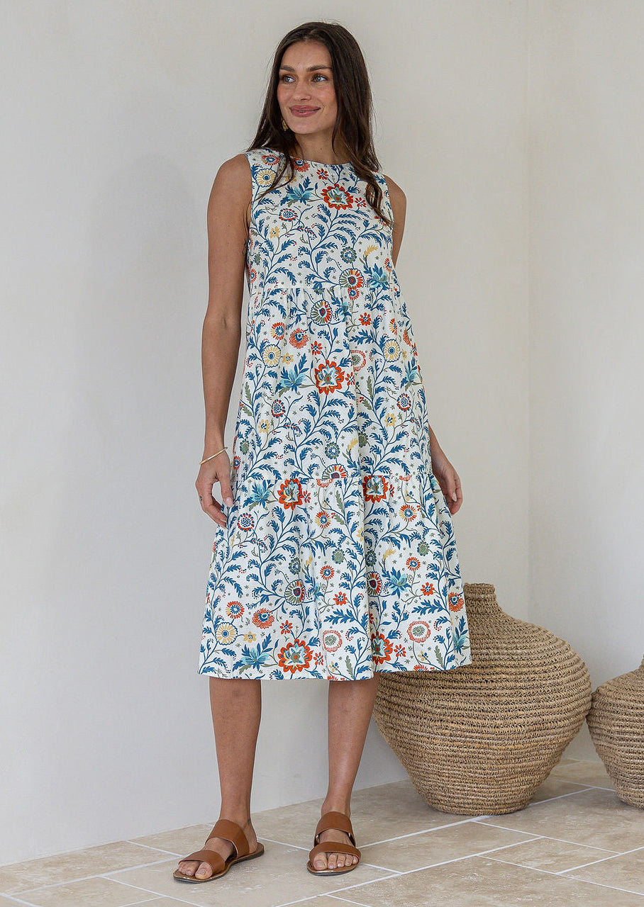 Model wears 100% cotton sleeveless midi dress with high round neckline, tiered design and pockets in white based floral print