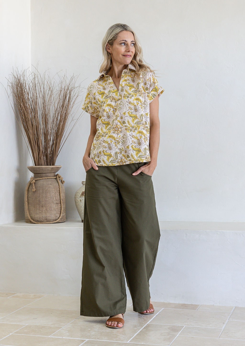 Woman wearing a floral 100% cotton top with short folded cuff sleeves paired with plain pants