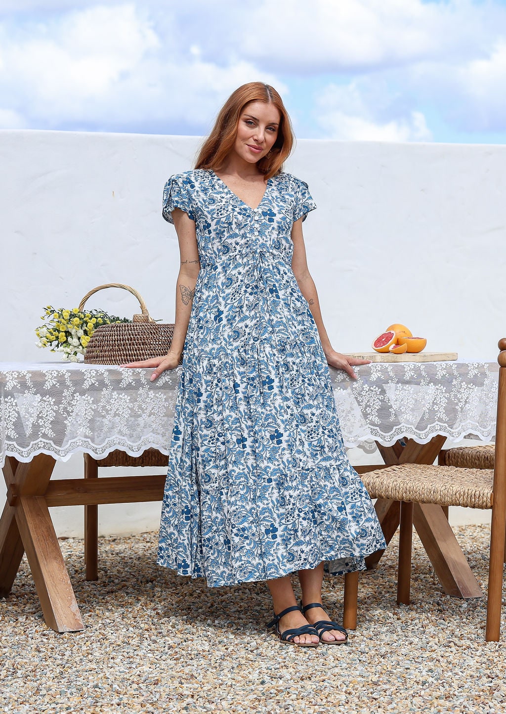 Blue and white floral print maxi dress with V-neck and cap sleeves, worn by model standing outdoors