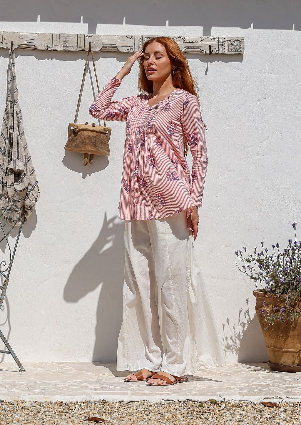 Woman wearing a Pink floral striped long-sleeve blouse with white pants.