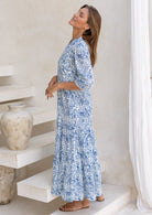 Model posing slight sideways in 3/4 sleeved long maxi dress with buttoned bodice and pockets.