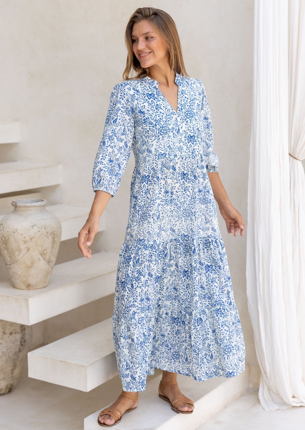 Woman wearing a blue floral maxi dress with 3/4 sleeves, buttoned bodice