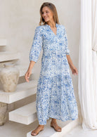 Woman wearing a blue floral maxi dress with 3/4 sleeves, buttoned bodice
