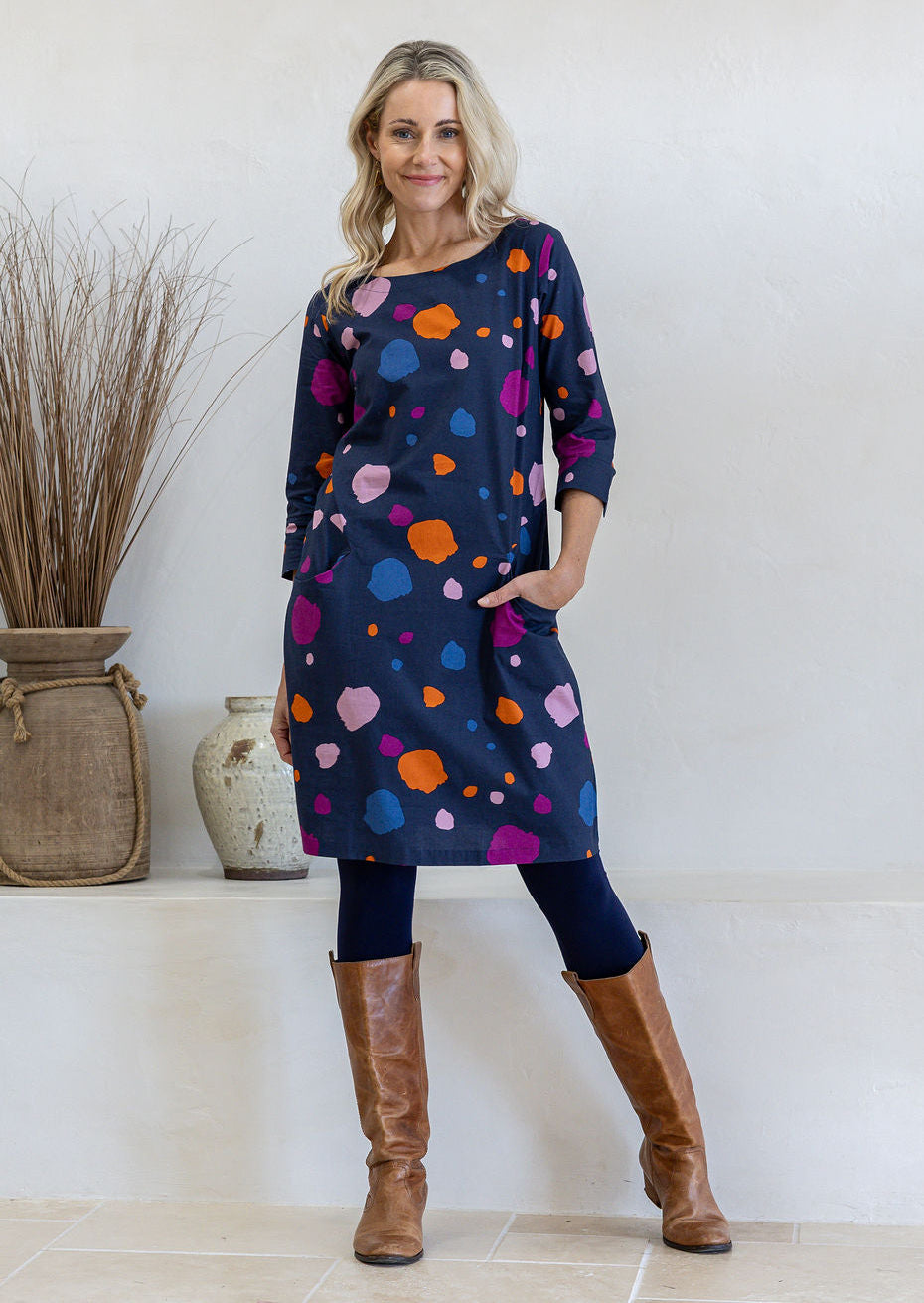 Model standing with one hand in pocket wearing 100% cotton dress in bold and colourful printed dress.