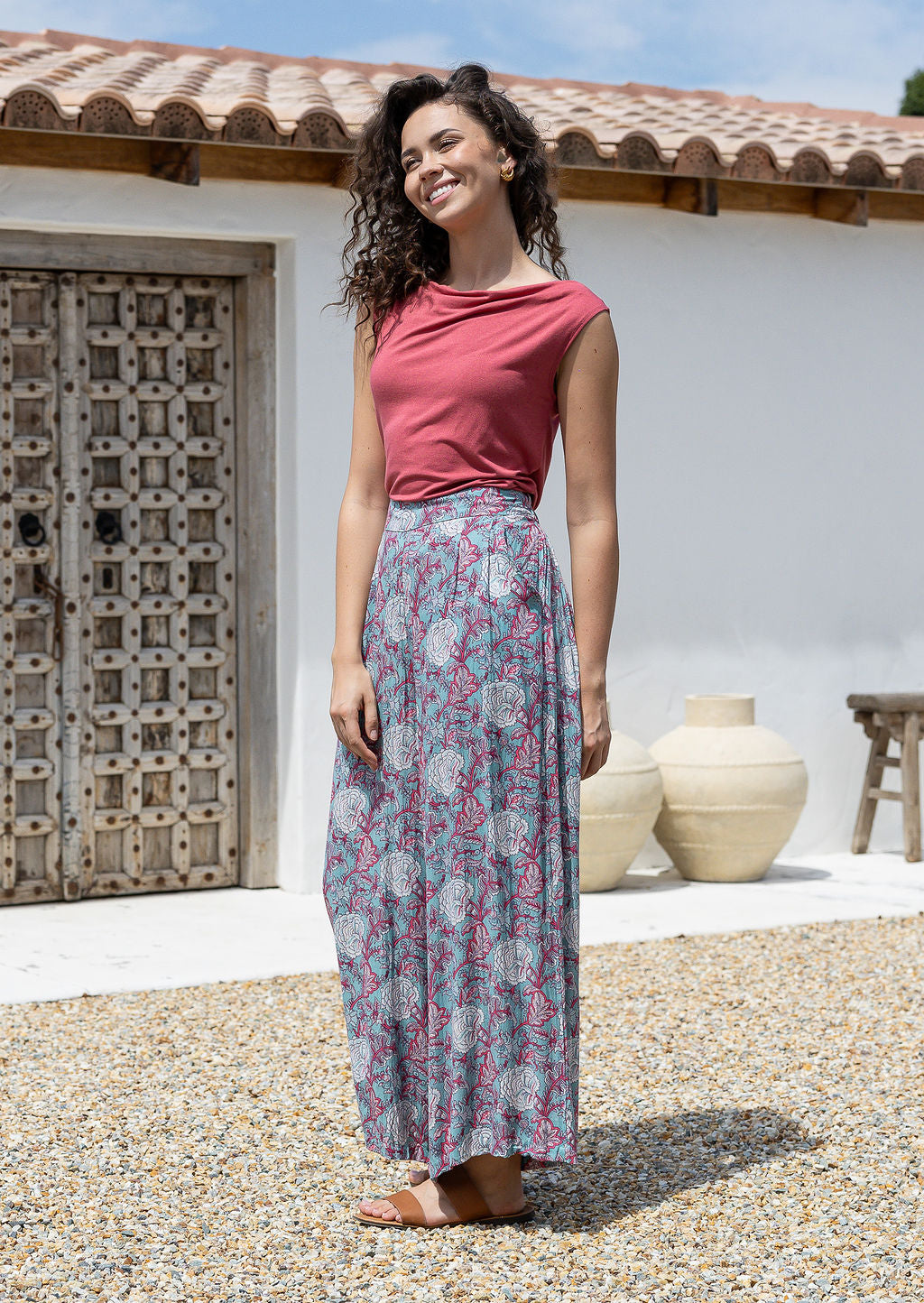 woman stands sideways wearing a wide legged rayon pants with blue based pink and white floral print.