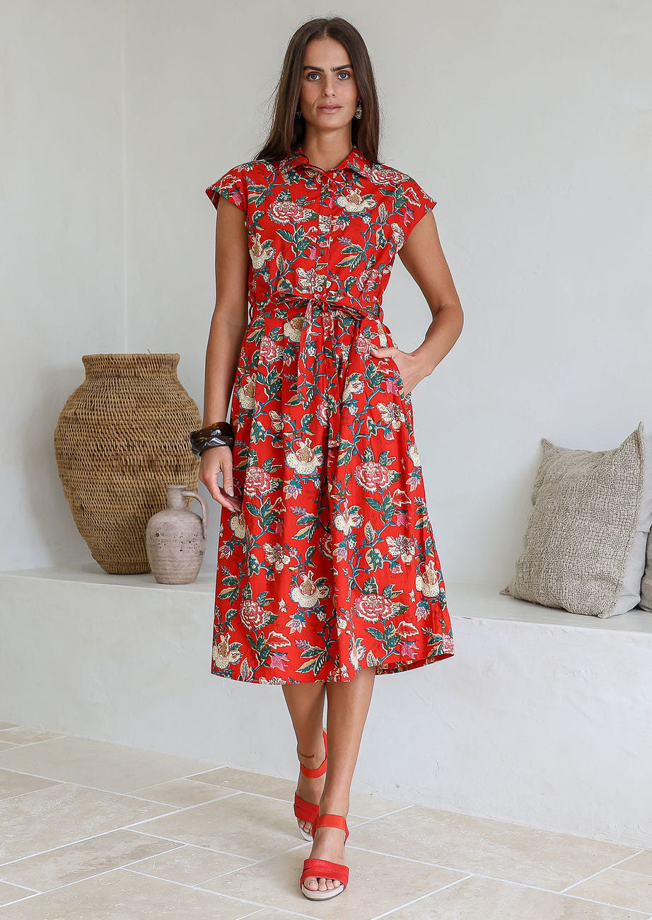 Woman wearing a shirt style cotton midi length dress with buttoned bodice, pockets, collar and cap sleeves