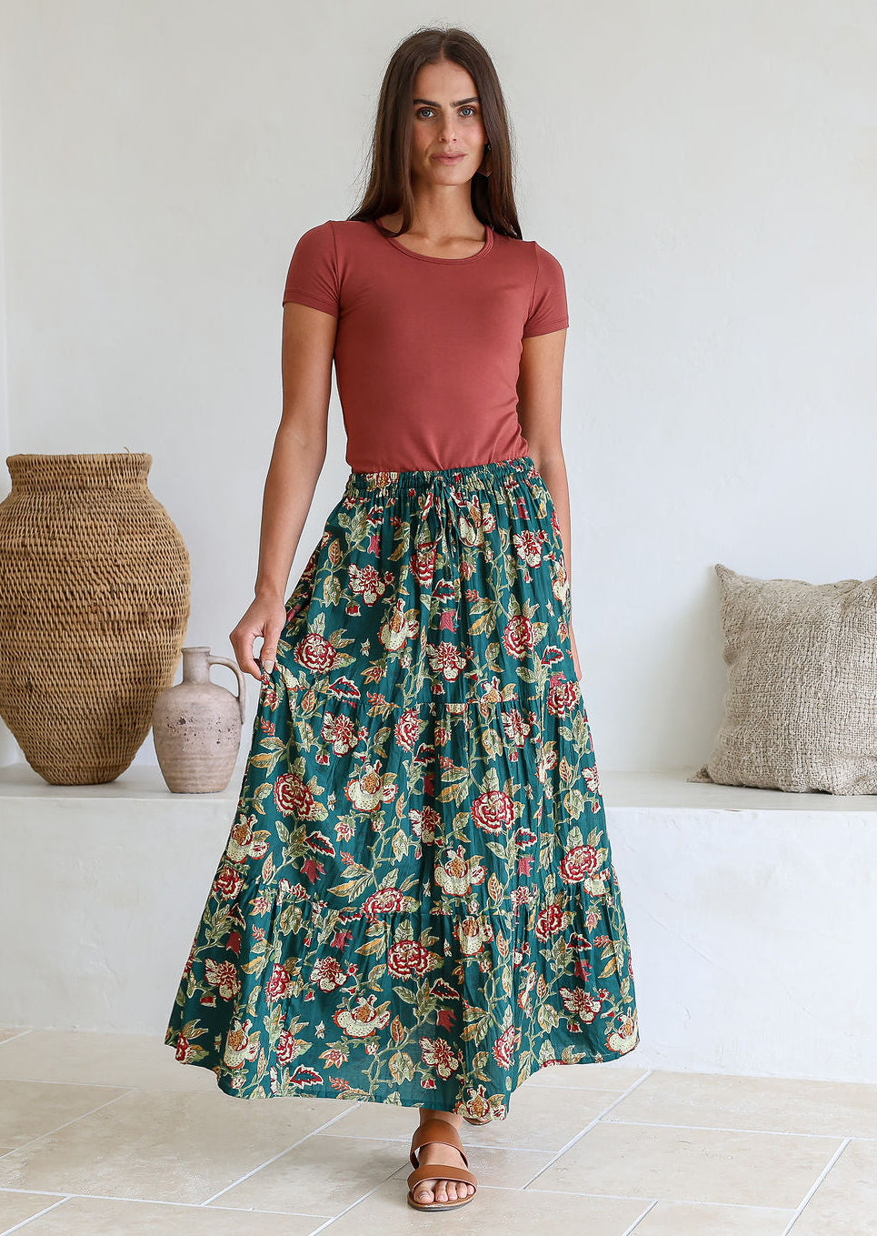 Woman wearing a bottle green based floral print 100% cotton maxi skirt with an elastic waistband and a drawstring