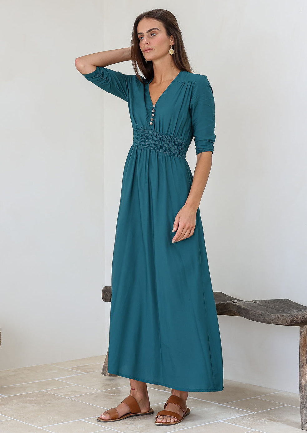 Woman wearing a teal rayon maxi dress with a ruched waistband, buttoned bodice, and a V-neckline