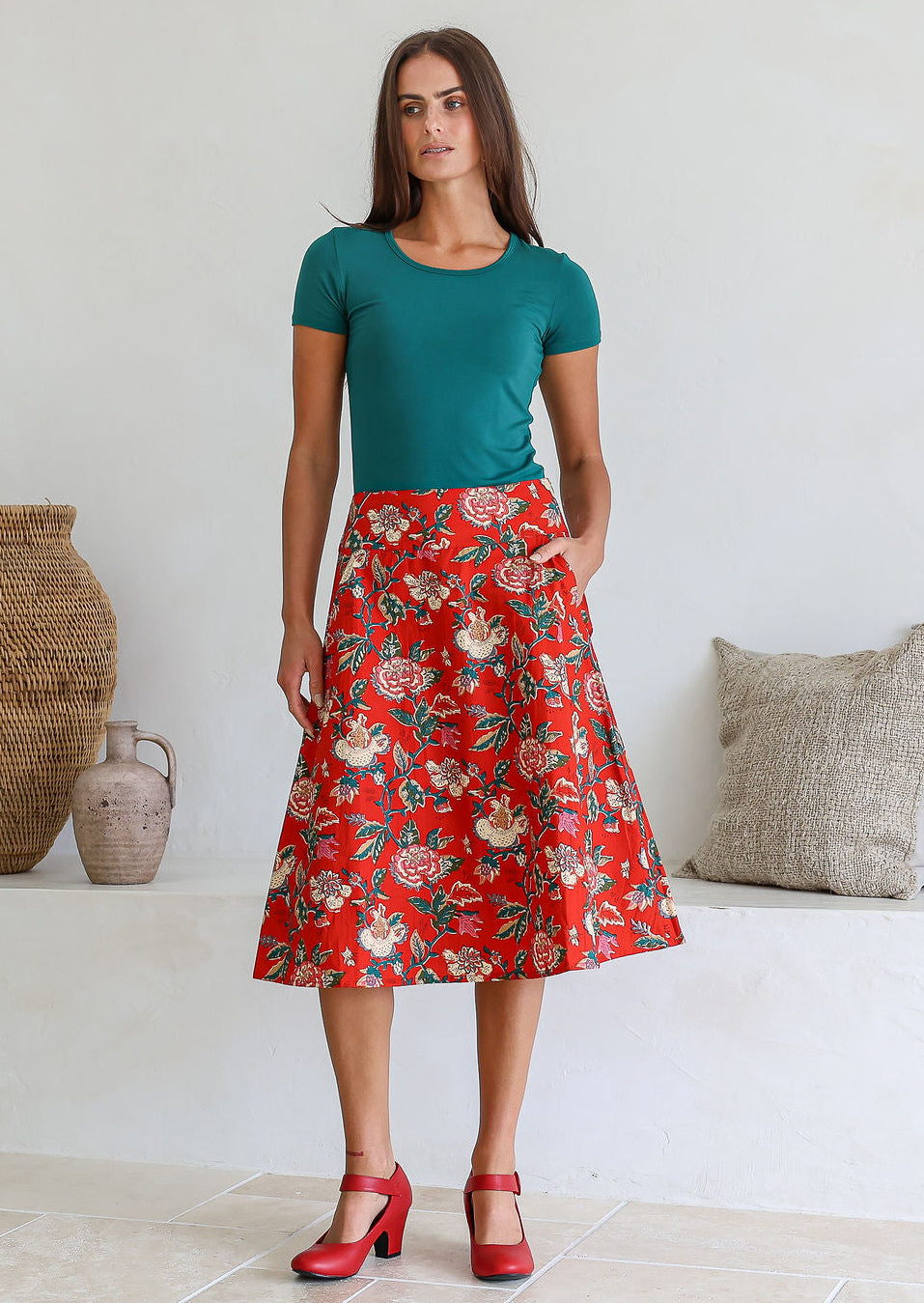 Woman is posing with one hand in pocket wearing a 100% cotton red a-line skirt.