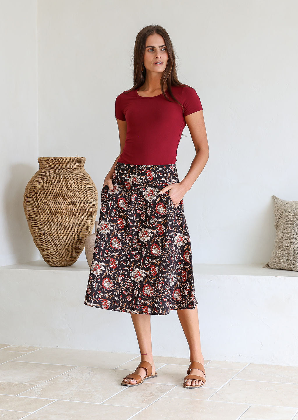 Model wearing 100% cotton knee length A-line skirt with side zipper and pockets in black based traditional Indian design print