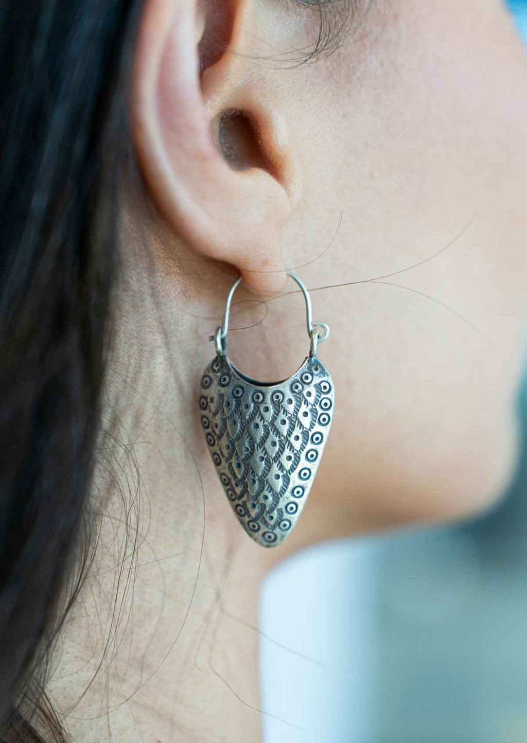 Close-up of a person wearing a textured Hill Tribe Silver hooped earring.