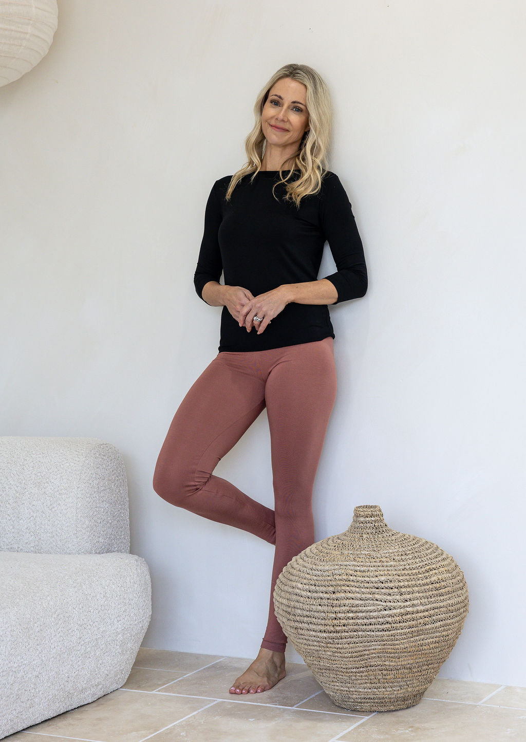 Woman wearing a 100% rayon soft stretch jersey leggings in dusty pink colour standing in a minimalistic room.