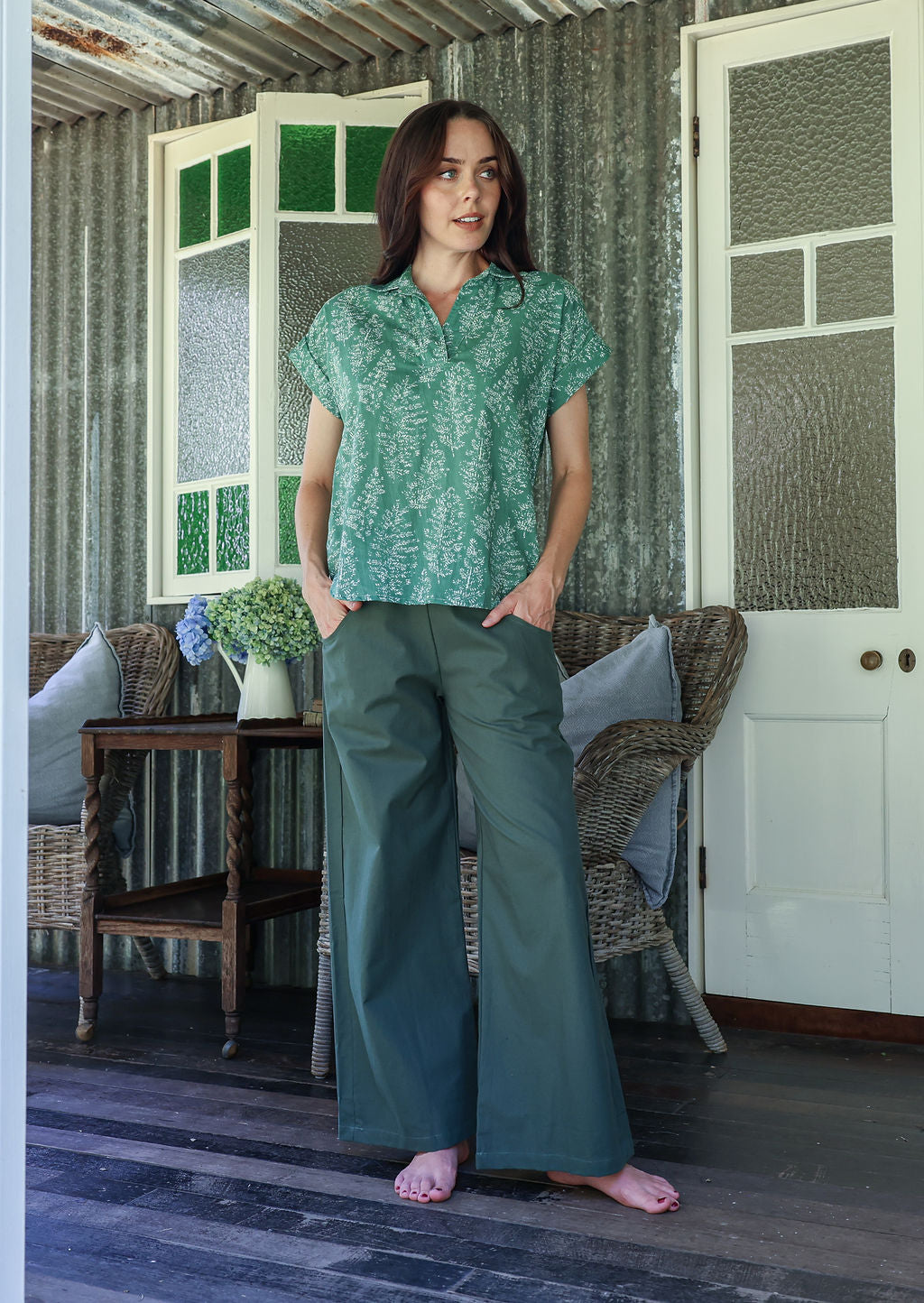 Woman wearing a floral cotton top with short folded cuff sleeves, collar and V neckline